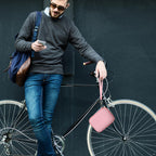 Person carrying the light pink power bank case beside a bicycle